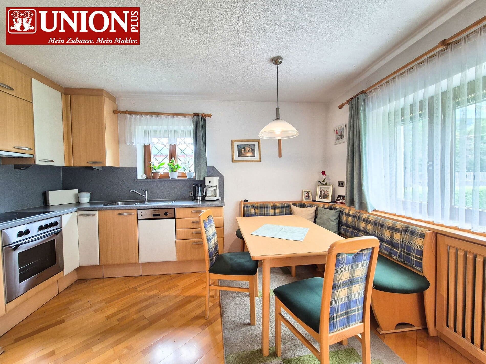 Gemütliche Küchen- und Essbereich in einem gepflegten Zuhause mit Holzfußboden, aktueller Ausstattung und viel Tageslicht durch große Fenster, ideal für Familien und Gäste.