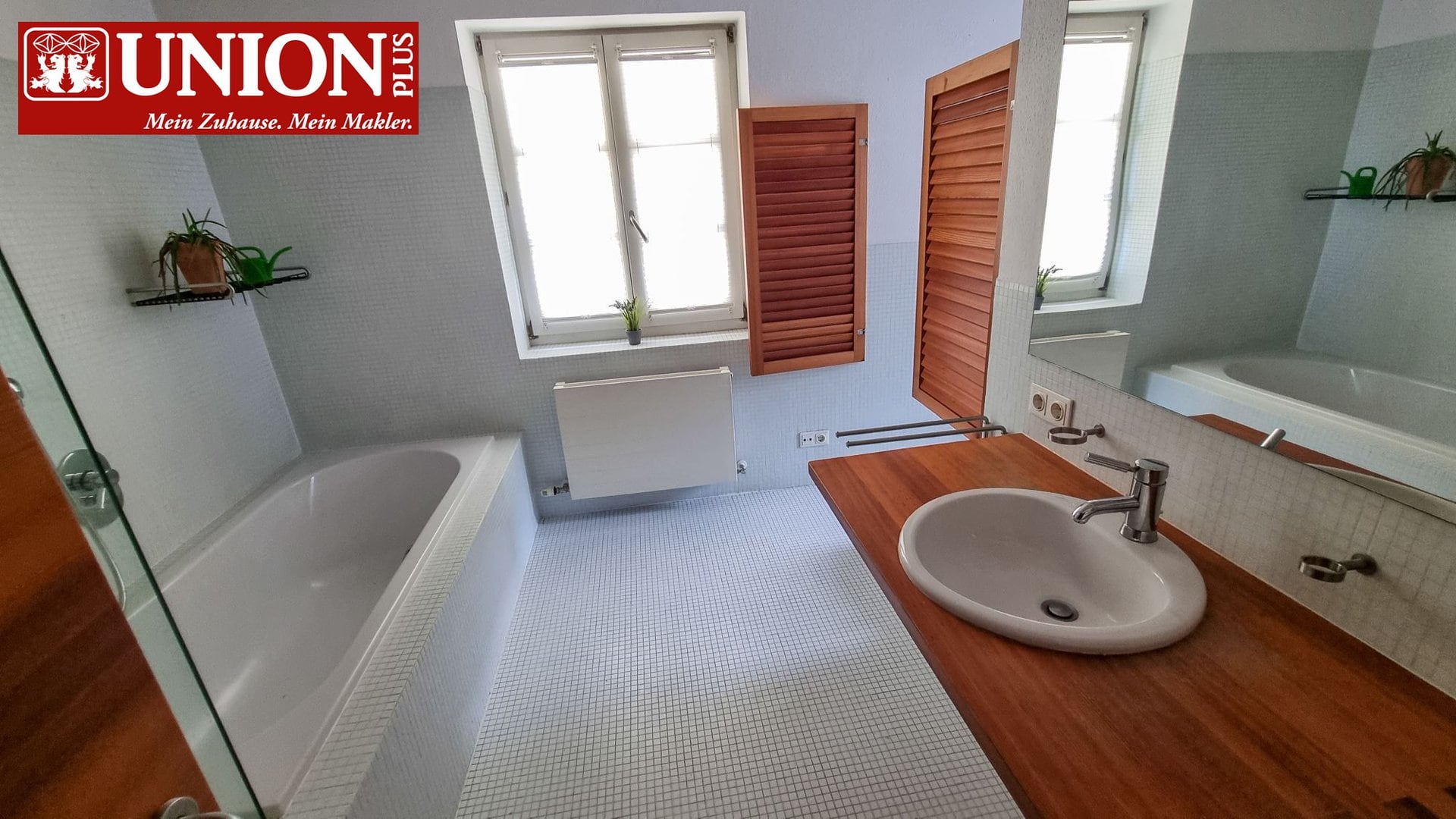 Moderner Badezimmerraum mit Badewanne, Holzschränken und großen Fenstern, bereit für Sanierung oder Renovierung, ideal für Immobilienmakler und Hausbesitzer, die Komfort und Stil suchen.