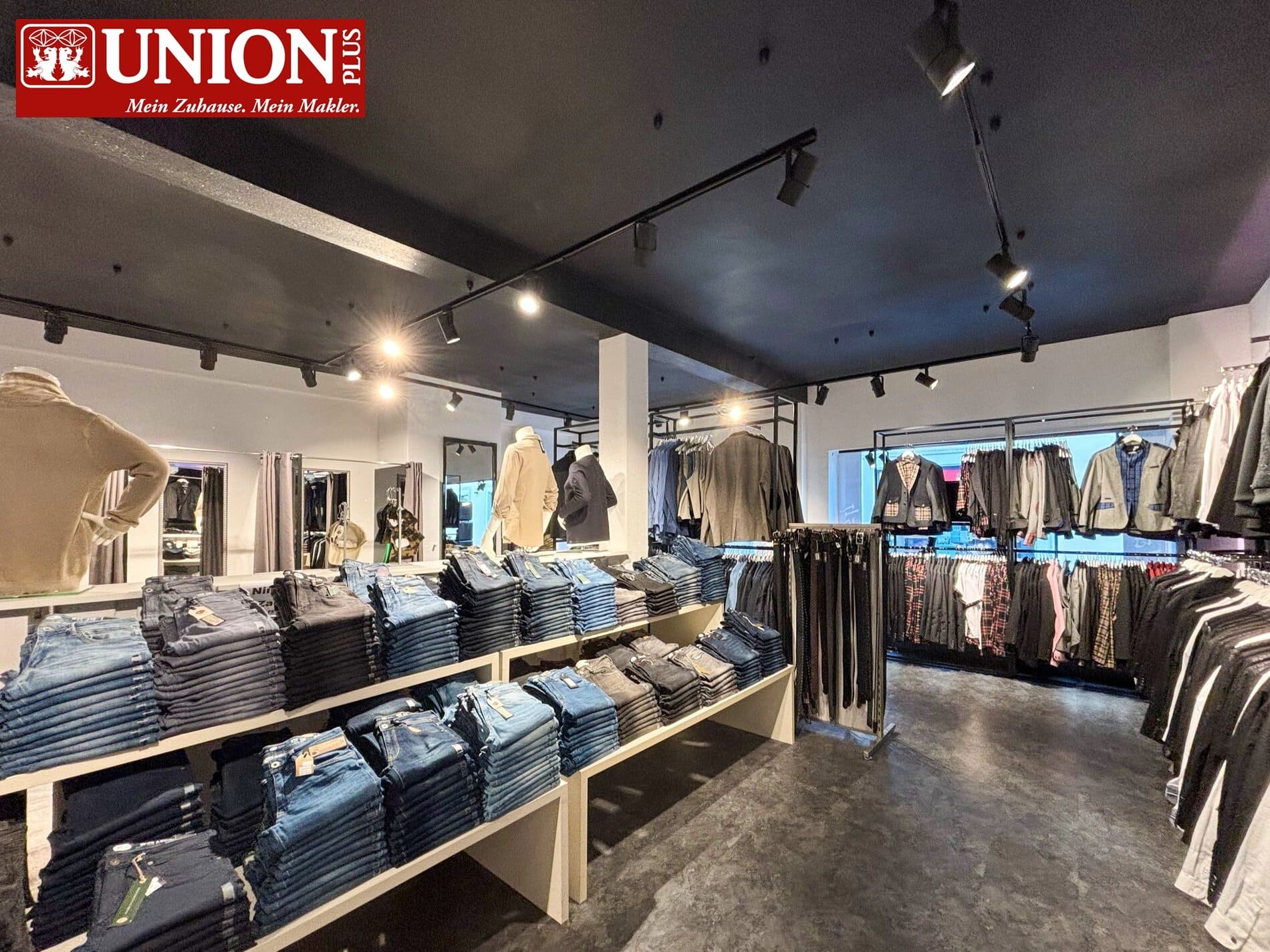Ein stilvolles Modegeschäft mit vielfältigen Herren- und Damenbekleidung, darunter Anzüge, Hemden, Jeans und Mäntel. Die moderne Ladenfläche ist optimal ausgeleuchtet und lädt zum entspannten Shoppen ein, ideal für modebewusste Kunden in Österreich.