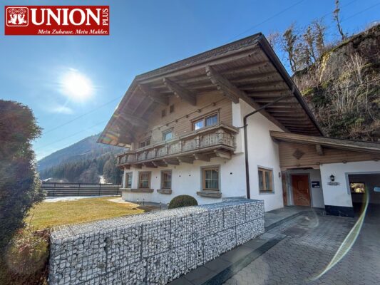 Charmantes Chalet im alpinen Stil mit Holzdetails und Balkon, umgeben von Natur, bei sonnigem Himmel. Perfekt für Erholung in den Bergen.
