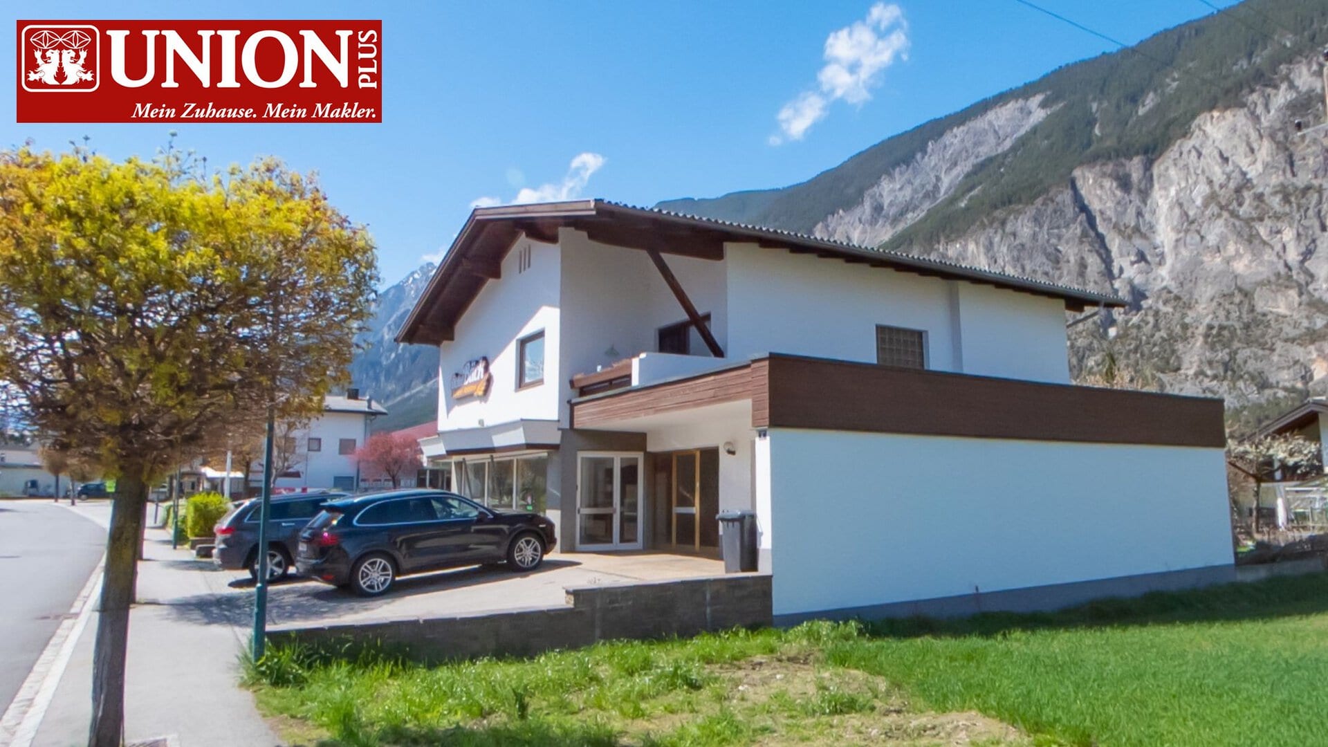 Haus in den Bergen mit Parkplatz, umgeben von Natur und Bäumen, ideal für Erholung und Ruhe.