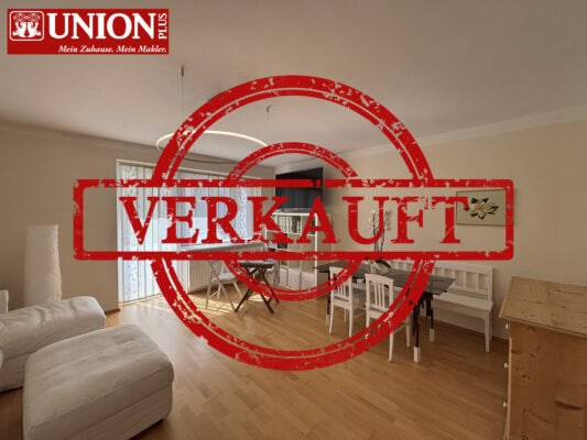 Modernes Wohnzimmer mit offener Küche, hellem Holzfußboden und großen Fenstern, ideal für Immobilienverkauf.